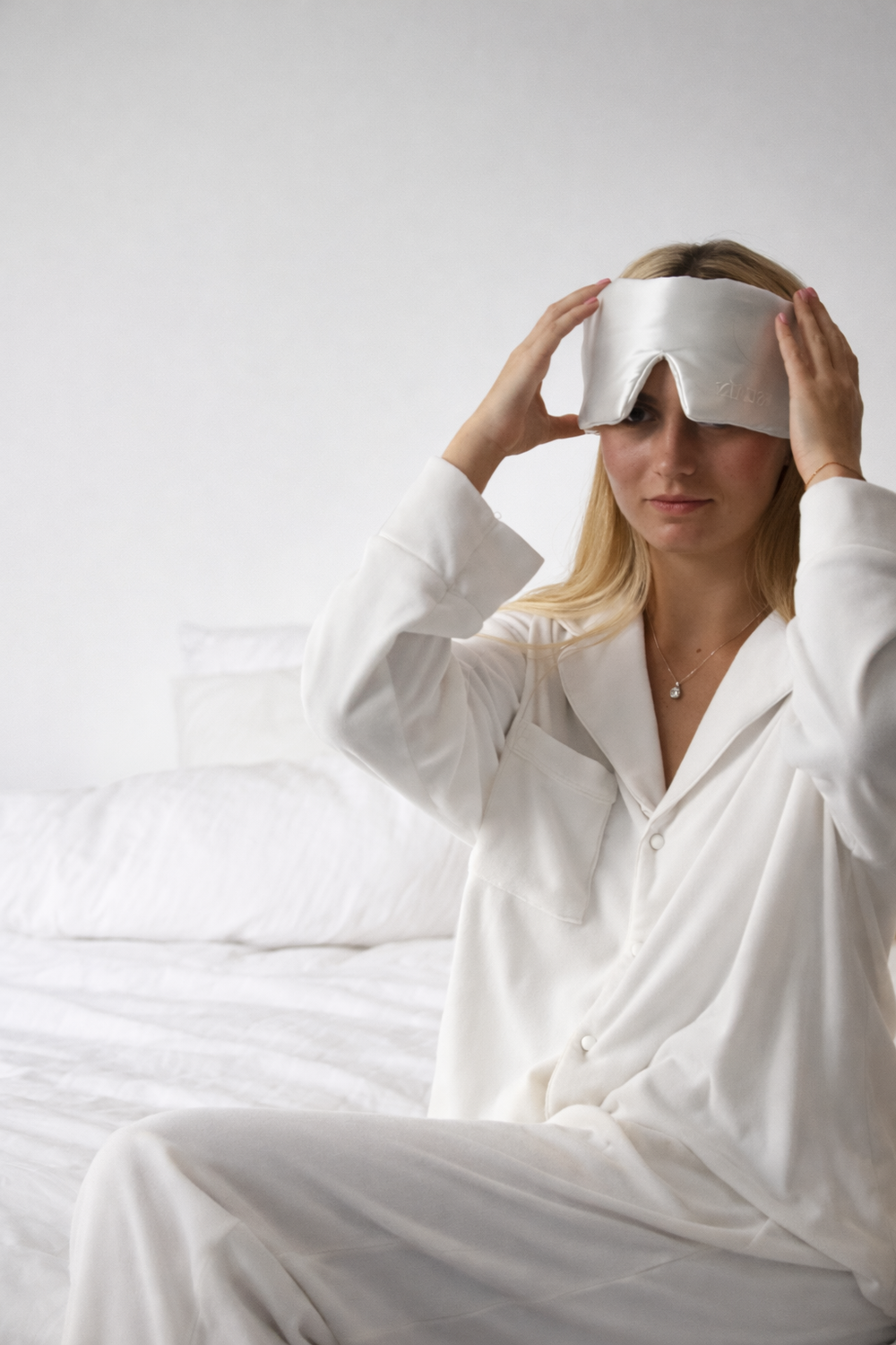 Smiling woman holding a pink Still Suain silk sleep mask