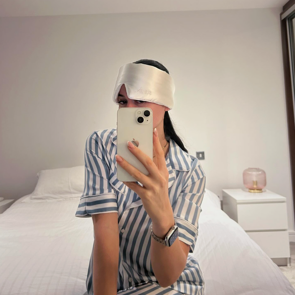 Woman in striped pyjamas taking a mirror selfie in a Still Suain silk sleep mask